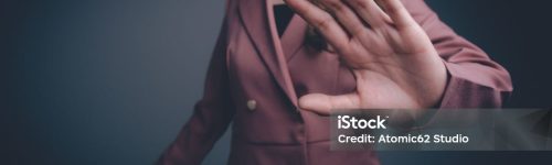 A businesswoman in a pink suit holds her hand out to stop something.